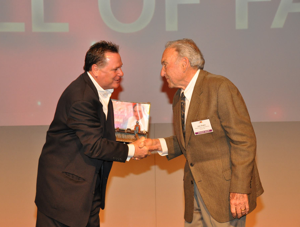 Joe Zukin shaking a hand and being presented with OAAA Hall of Fame Award