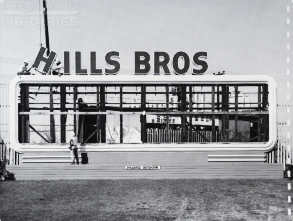 A crane-aided crew positions lettering on top of a billboard.