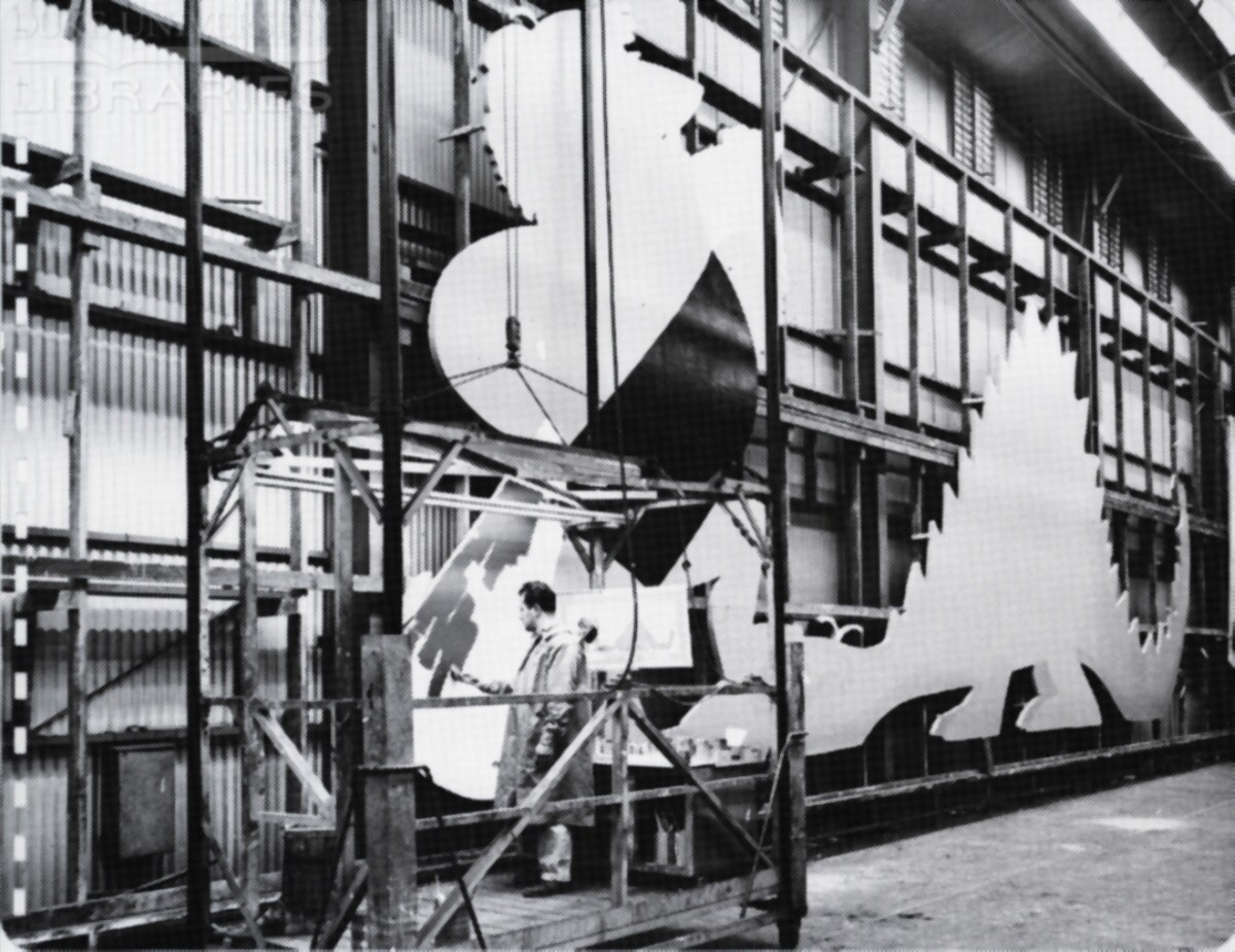 A senior sign painter is painting a billboard panel cutout.