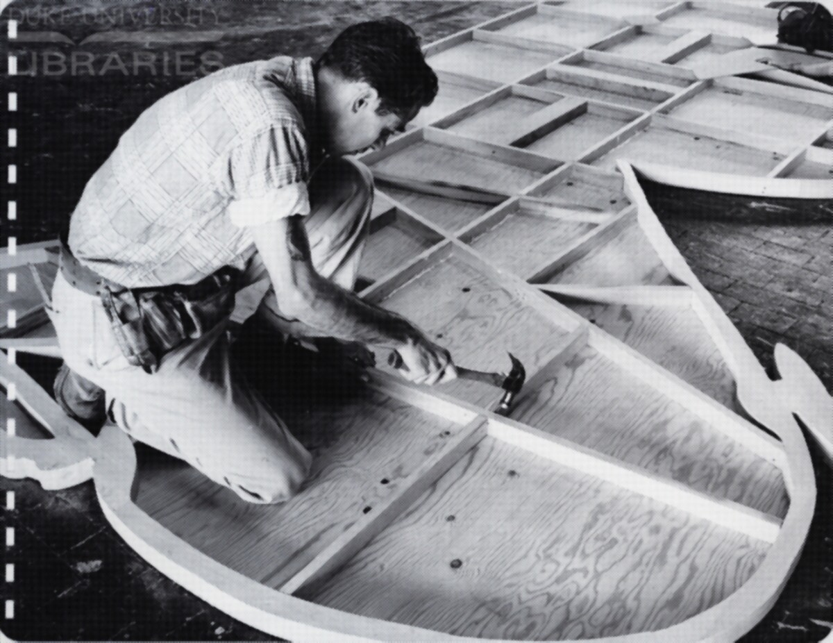 A worker assembles a billboard cutout and installs backing reinforcement.