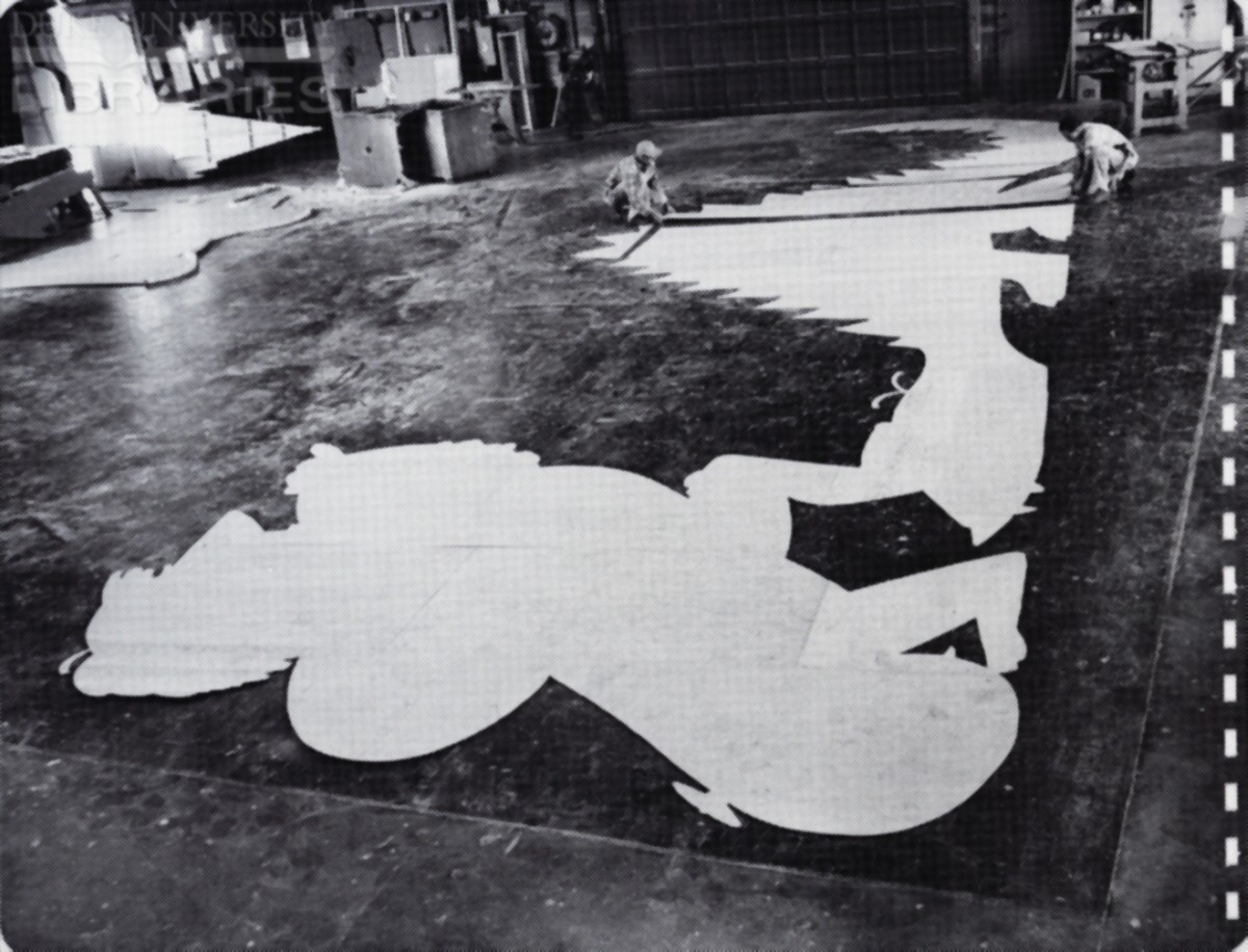 A billboard construction crew checks wooden cutouts for accuracy before they are assembled and reinforced.