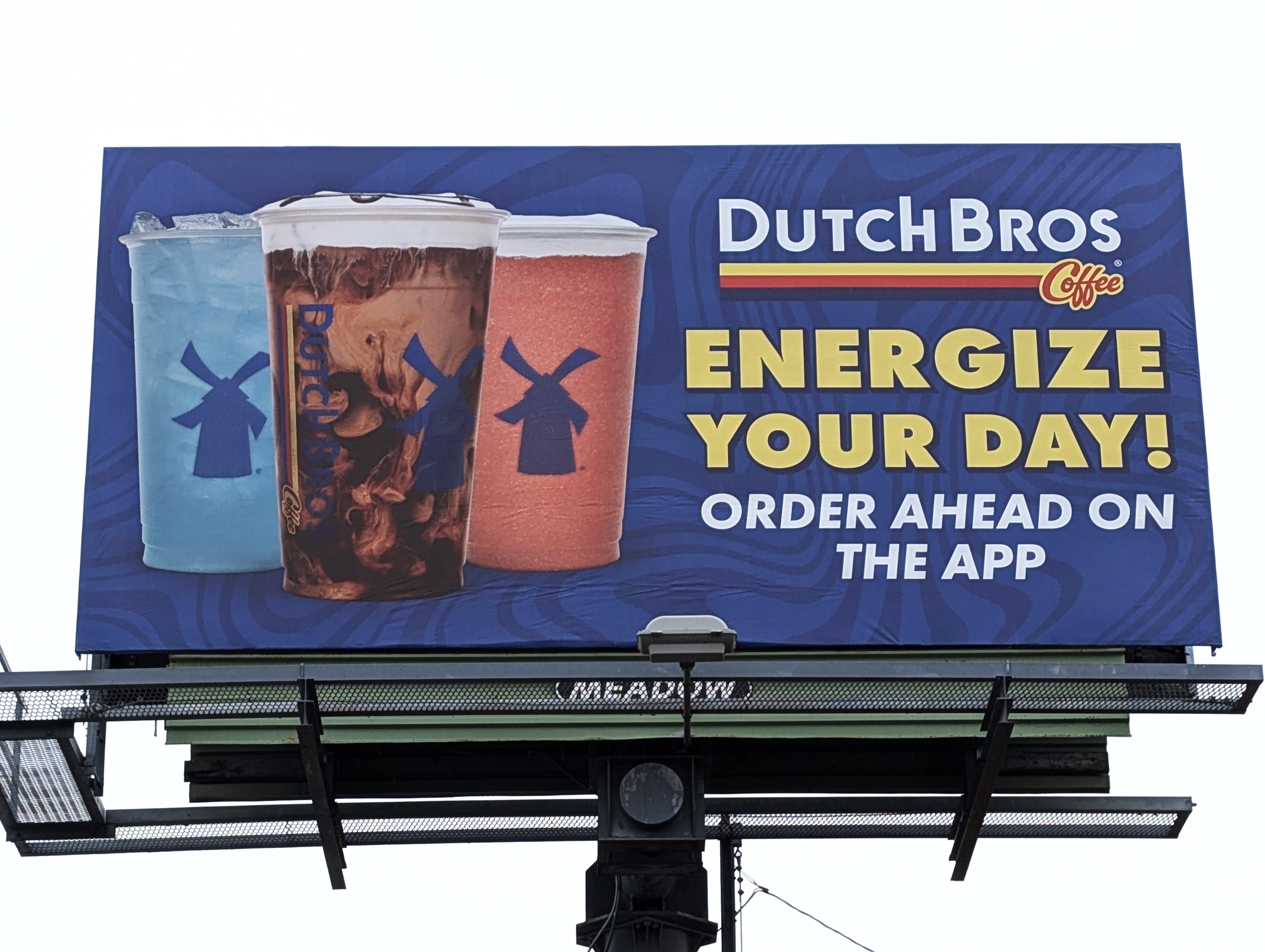 Blue billboard featuring drinks from Dutch Bros Coffee that says "Energize your Day!"