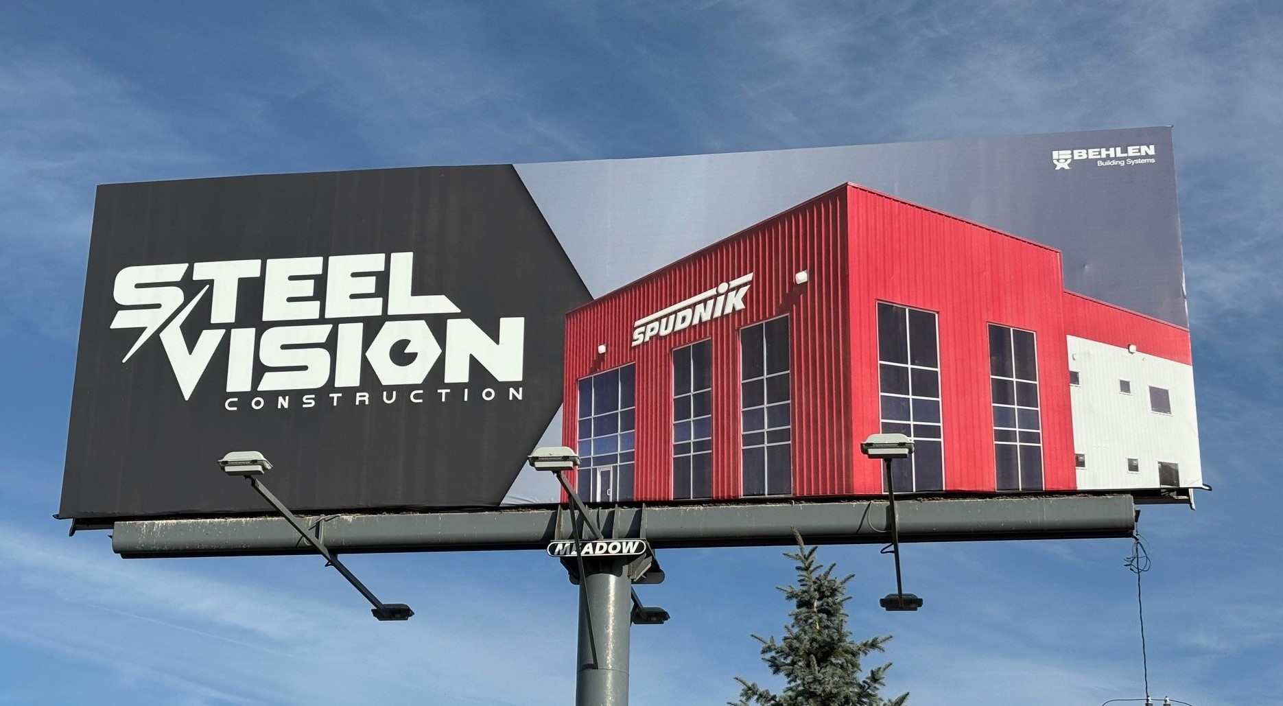 Billboard advertising Steel Vision Construction featuring logo and red warehouse