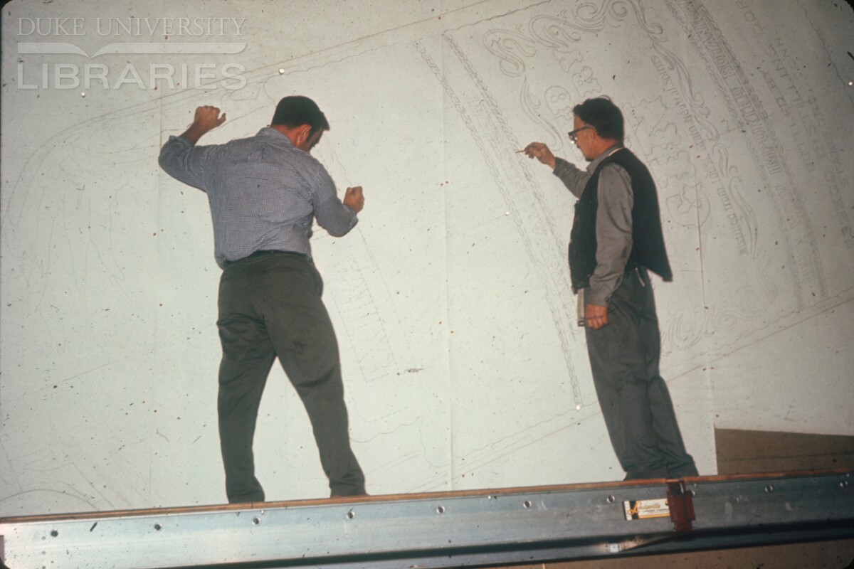 Two artists drawing out a full-size billboard design.